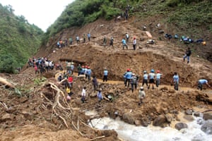Rescue workers and volunteers clear debris and mud after Typhoon Goni hit Mankayan