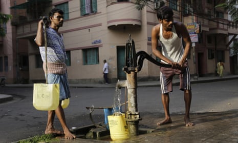 Men get water from a roadside pump in Kolkata, India