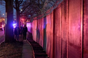 Pedestrians walk next to the razor-topped fence around the Capitol building
