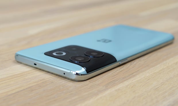 The OnePlus 10T lying flat on a table showing its molded glass back in a light blue-green colour.