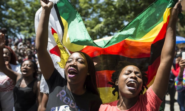 Women hold a Zimbabwean flag at a rally