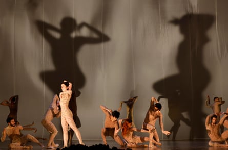 The cast of Ihsane dance wearing flesh-coloured, patterned body suits, they spotlit from below, casting large shadows on the backdrop