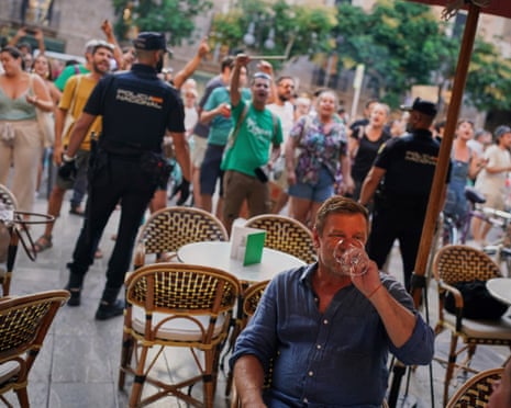 Tourists sit in a restaurant as people protest against overtourism in the Balearic island of Mallorca, Spain.