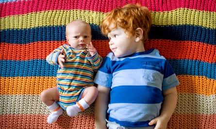A baby and a young boy lying on a blanket