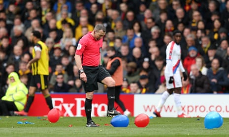 Referee Kevin Friend pops balloons on the pitch.