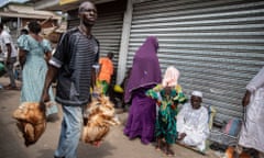 A man carrying chickens on a street in Ghana