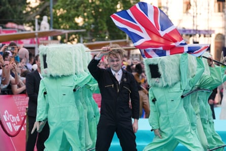 LookMum No Computer holds union jack with several performers in turquoise ‘computer’ outfits with screens for heads.