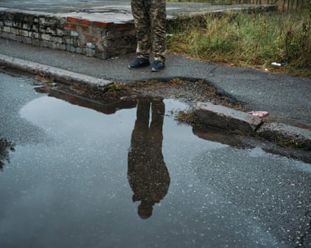 The reflection of a man in a roadside puddle