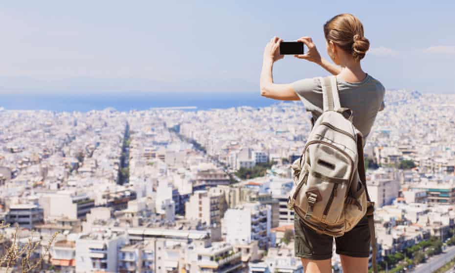 Young woman taking a picture over a city with her mobile phone