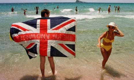 Tourists holding union jack on the beach at Benidorm, Spain.