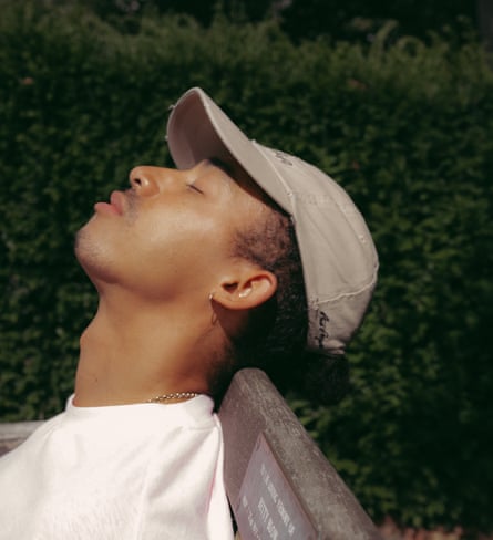 Jordan Stephens resting his head on the back of a park bench, his eyes closed