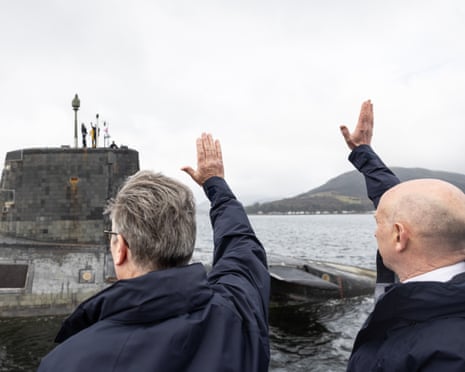 Keir Starmer and John Healey waving with a submarine in the background