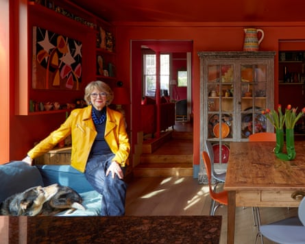 Woman in yellow jacket in her art-adorned red kitchen