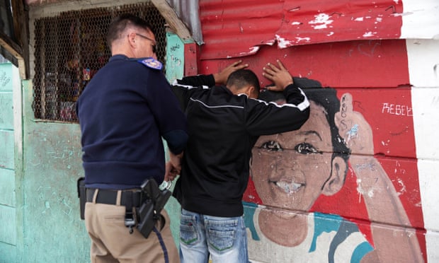 A member of the Metro police gang unit searches a young man