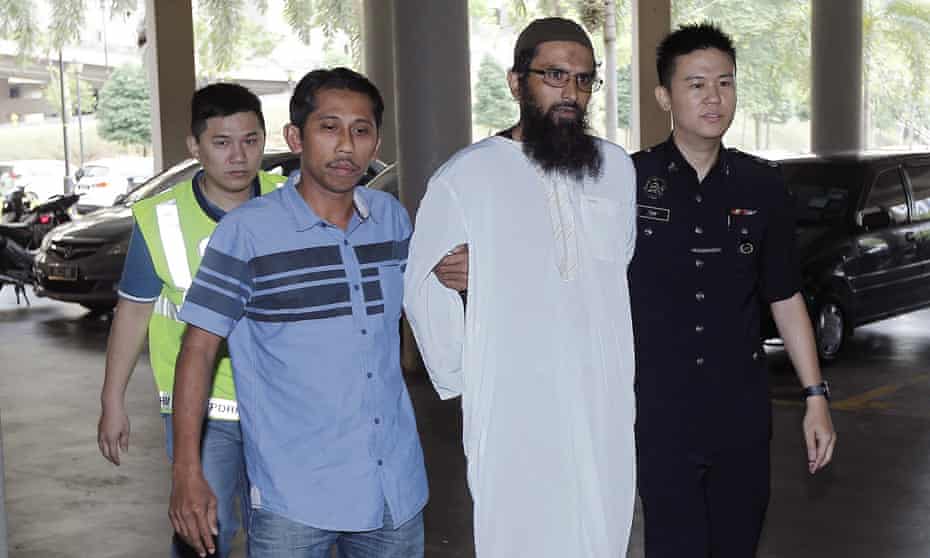 Salah Salem Saleh Sulaiman, a Danish national, is escorted by police to a court in Kuala Lumpur.