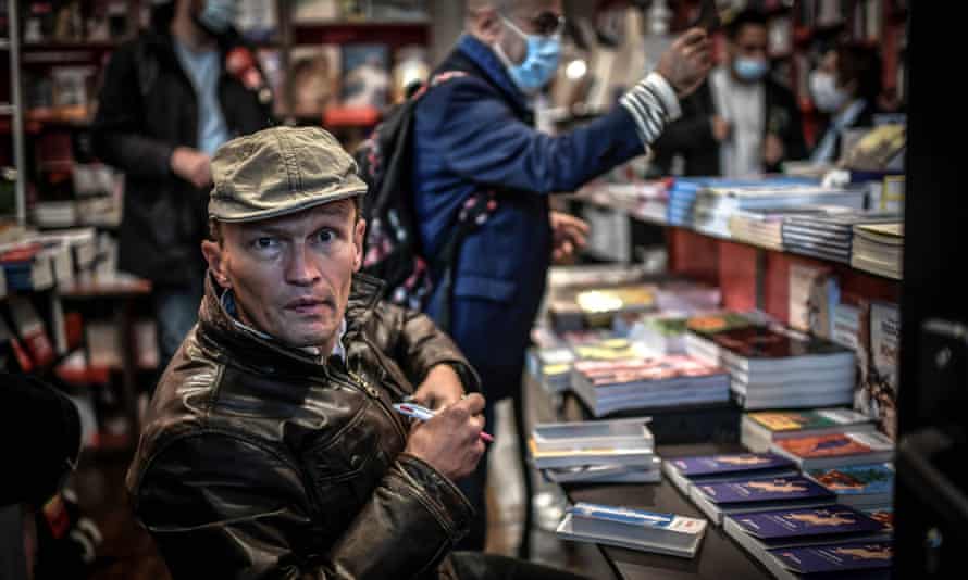 French writer Sylvain Tesson poses inside the Librairie des Abbesses bookstore as he signs one of his books during the launch of “Rallumez les feux de nos librairies” (Turn back our bookstores’ lights) event on November 2, 2020 in Paris, on the fourth day of the second national general lockdown aimed at curbing the spread of Covid-19. Small book traders are forced to shut up shops for a second time this year during what is usually a busy time for retailers in the run-up to the year-end holidays. Owners of bookshops and other specialist outlets complained that the month-long lockdown that came into effect on October 30, 2020 to curb a second wave of infections discriminates against small traders already struggling to survive.