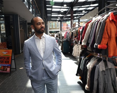 Josh Babarinde walks past rows of clothing racks