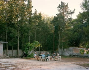 Men playing cards in a backyard with trees behind the walls