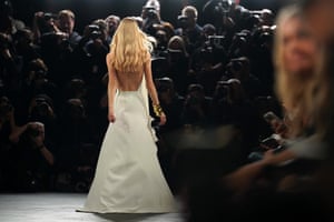 A model in a pale-coloured dress faces assembled photographers