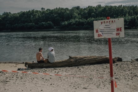 A sign on a beach telling people not to swim in a polluted river.