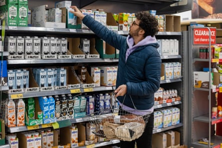 a man grabbing a milk container on a shelf