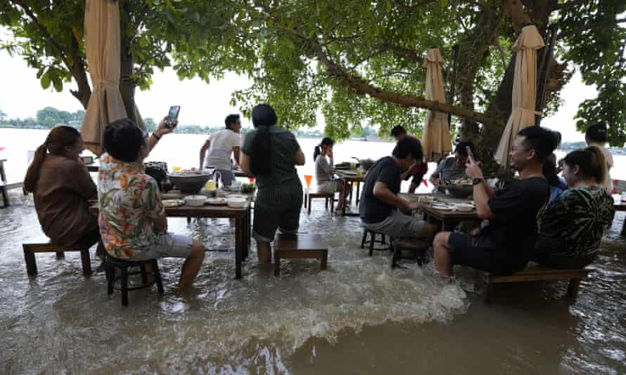 Customers at the Chao Phraya International Cafe in Nonthaburi react as the wake from a passing boat surges through the restaurant.