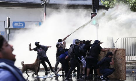 Protests against Chile’s government in Santiago<br>Demonstrators take cover as they are sprayed by security forces with a water cannon during a protest against Chile’s government in Santiago, Chile November 12, 2019. REUTERS/Ivan Alvarado