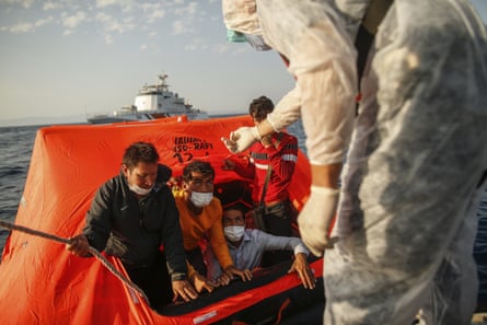 Turkish coastguard officers talk to migrants on a liferaft