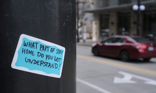 A sticker referncing advice by officials to stay home aodrns a light post in Seattle, Washington. 