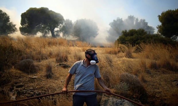 A local tries to extinguish a wildfire burning in Markati on 16 August.