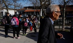 A man walks pasts schoolchildren from nearby villages waiting to be escorted to the the primary school, which serves 17 villages, in the village of Dikaia, Greece, March 29, 2024