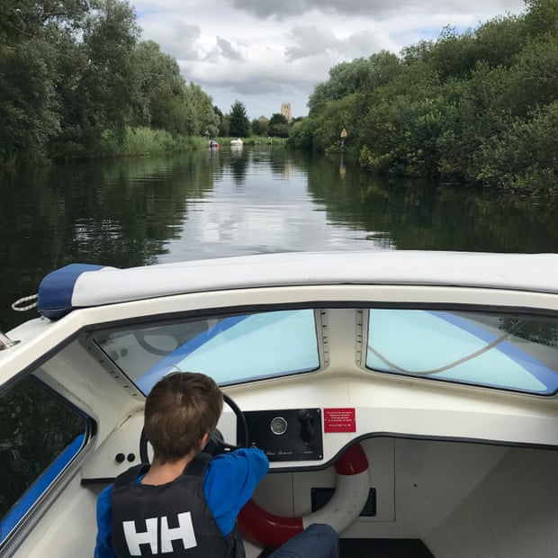 The writer’s son pilots their electric boat along the river, Suffolk, UK.