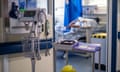 general view of medical equipment on a NHS hospital ward in London including monitors and medication in trays; an anonymous, blurred image of a patient in a bed by a blue curtain can be seen in the background