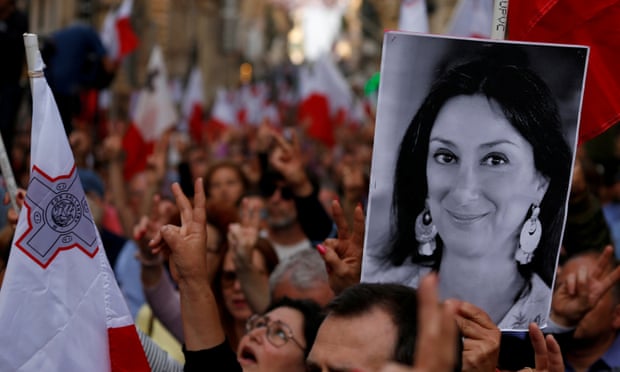 A protester carries a photo of Maltese anti-corruption journalist Daphne Caruana Galizia, who was killed by a car bomb