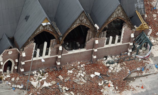 A man rides past a destroyed church in Christchurch, New Zealand.