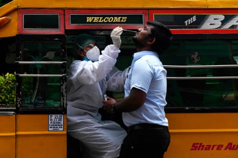 A health worker wearing Personal Protective Equipments (PPE) suit, sits in a share auto-rickshaw as she collects a swab sample from a man to test for the Covid-19 coronavirus, outside a commercial centre in Chennai, India on 12 September, 2020.