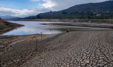 A water company worker monitors the level of the San Rafael reservoir. The landscape is arid and cracked