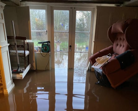 A flooded room with water above the sill of a French door and chairs on shelves or raised diagonally against a wall