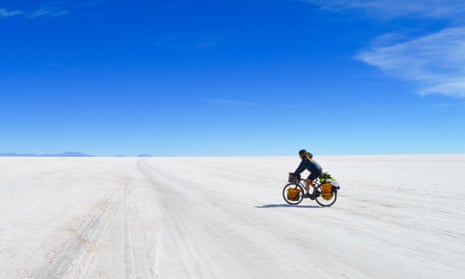 Laura Bingham, pictured cycling across a snowy landscape on a blue-sky day. She cycled across South America, surviving purely on the kindness of strangers
