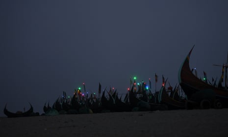 Night lights shine on fishing boats on the shore near Shamlapur Rohingya refugee camp