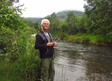 Taxonomist Art Borkent stands next to a river surrounded by greenery.