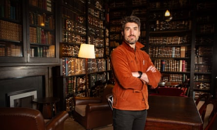 Thom Keep standing in Portico library with ornate book-linked shelves behind him