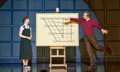 Patsy Ferran as Eliza Doolittle and Bertie Carvel as Henry Higgins either side of a chart that Carvel points to with a stick, in Pygmalion at the Old Vic.