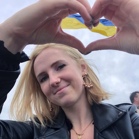 woman doing a heart sign through which a Ukraine flag can be seen 