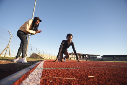 Leloba adopts the starting position on a track as her mother cheers beside her