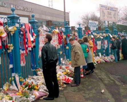People observe tributes of flowers and scarves left for the victims.