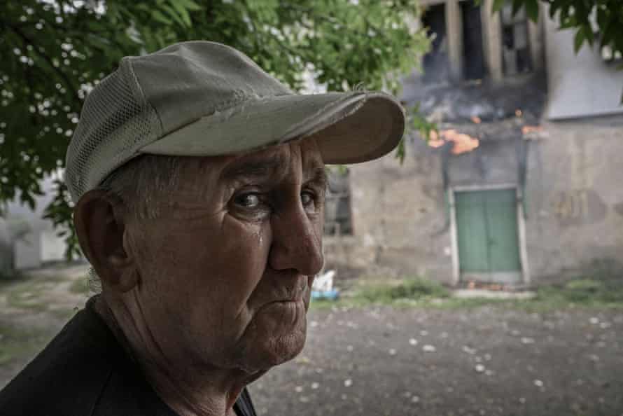 An elderly man watches the apartment building where he lives in Lysychansk as it burns after shelling.
