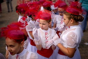 Children in red hats and white dresses congregate