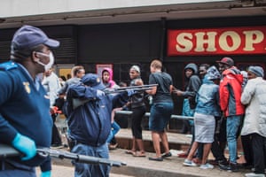 A policeman points a shotgun to disperse a crowd of shoppers in Yeoville, Johannesburg