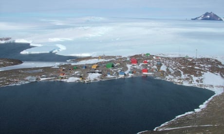Brightly coloured building on a rocky shore with scattered ice